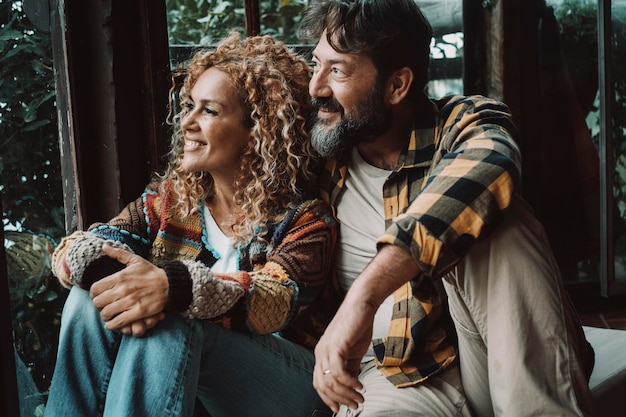 Pareja hombre y mujer de edad madura disfrutan y se relajan juntos en casa sentados en el suelo y mirando por la ventana. Adultos jóvenes felices en el estilo de vida del concepto de amor y relación