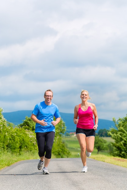 Pareja, hombre y mujer haciendo jogging o deporte al aire libre para fitness en la calle rural