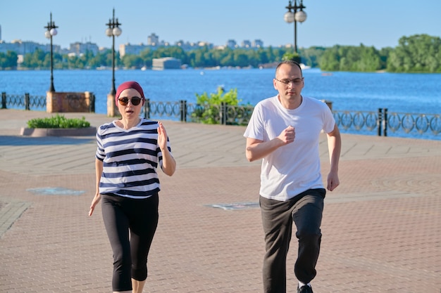 Pareja de hombre y mujer de mediana edad corriendo en el parque. Deporte, fitness, estilo de vida activo y saludable en personas de edad madura