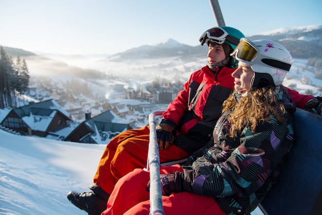 Pareja hombre y mujer snowboarders en un telesquí de cable