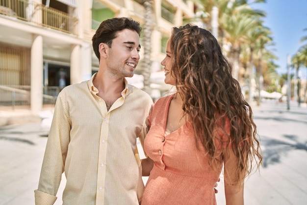 Pareja de hombre y mujer sonriendo confiados y abrazándose en la calle