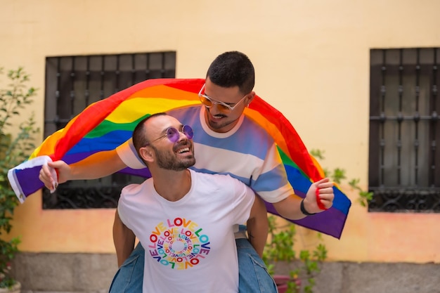 Pareja de hombres homosexuales cabalgando espalda con espalda en la fiesta del orgullo con el concepto lgbt de la bandera del arco iris