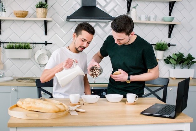 Pareja homosexual, personas homosexuales, matrimonio homosexual entre hombres caucásicos. Compañeros masculinos desayunando y cocinando en la cocina en casa