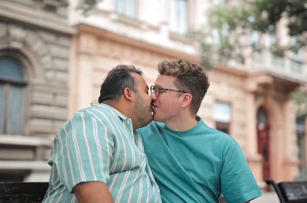 Foto pareja homosexual sentada en un banco se está besando