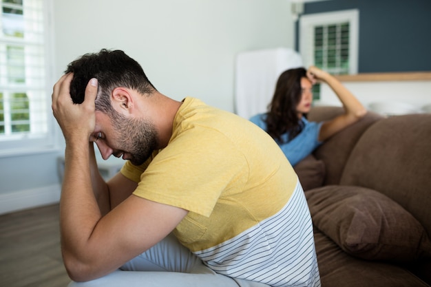 Pareja ignorándose en la sala de estar en casa