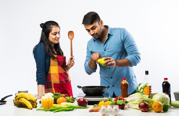 Pareja india en la cocina - Joven hermosa esposa asiática disfrutando de cocinar con su marido con una gran cantidad de verduras y frutas frescas