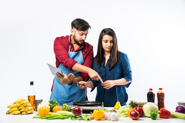 Pareja india en la cocina - Joven hermosa esposa asiática disfrutando de cocinar con su marido con una gran cantidad de verduras y frutas frescas