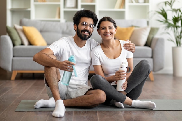 Pareja india deportiva haciendo ejercicio juntos en casa y posando en la cámara