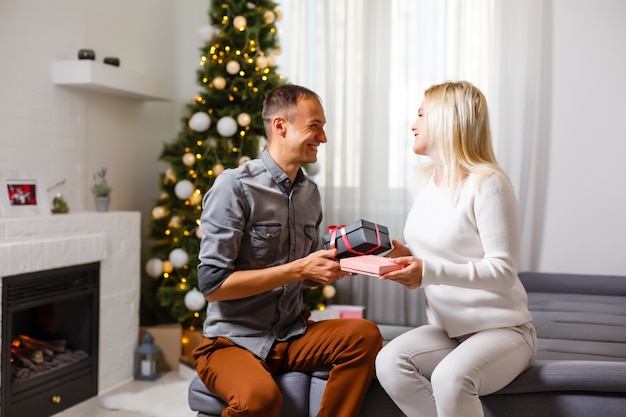 Pareja intercambiando regalos de Navidad cerca del árbol de Navidad.