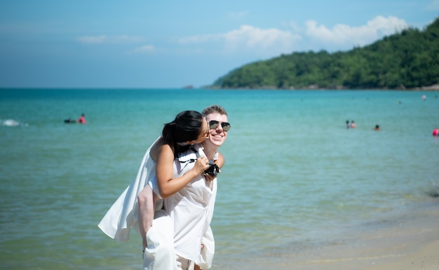 Una pareja interracial con la alegría de viajar al hermoso mar azul como el paraíso