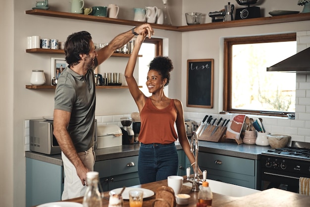 Foto pareja interracial baila y ama en la cocina para divertirse en el romance o pasar las vacaciones juntos en casa hombre y mujer felices bailando con felicidad alegre para una relación romántica o disfrutando de la casa de fin de semana