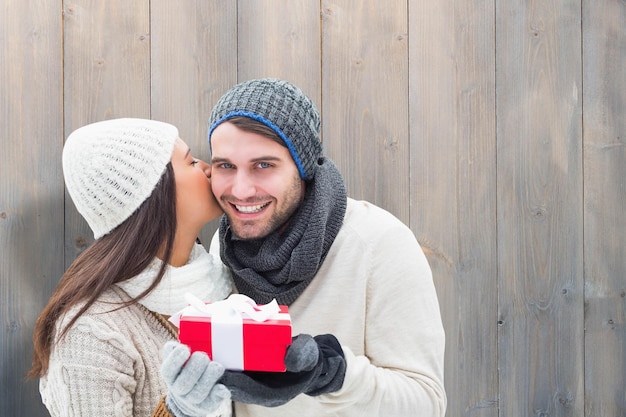 Pareja de invierno con regalo contra tablones de madera gris pálido