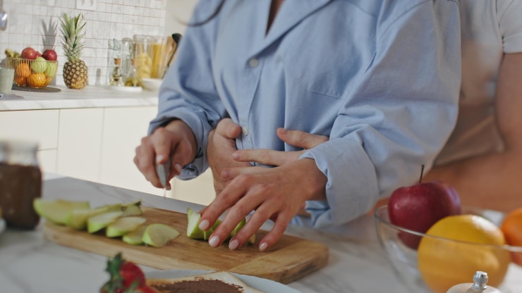 Foto una pareja irreconocible preparando comida en la cocina de cerca con las manos cortando manzanas.