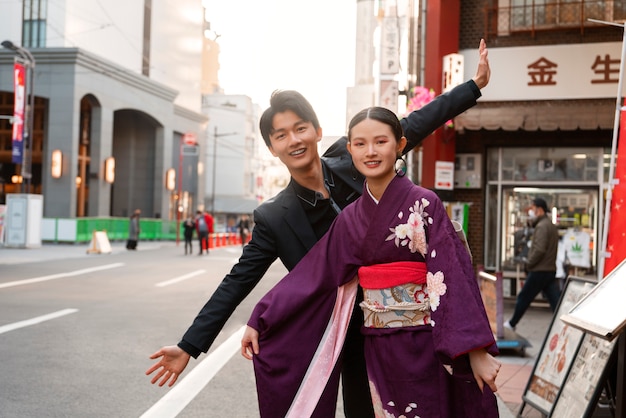 Foto pareja japonesa celebrando el día de la mayoría de edad y posando al aire libre en la ciudad