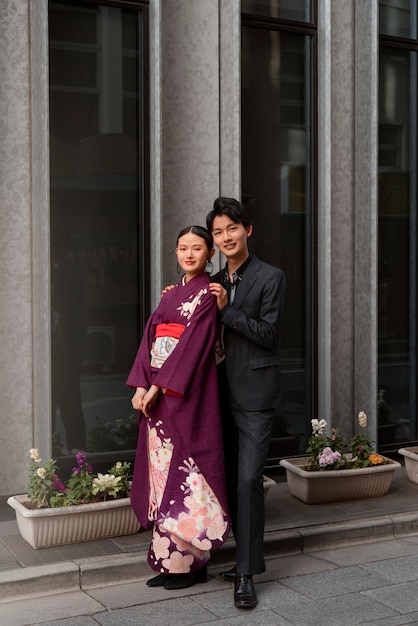 Foto pareja japonesa celebrando el día de la mayoría de edad y posando juntos en la ciudad