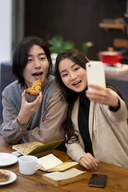 Pareja japonesa tomando selfie con pastel en un restaurante