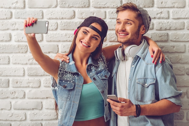 Pareja en jeans y gorras está haciendo selfie