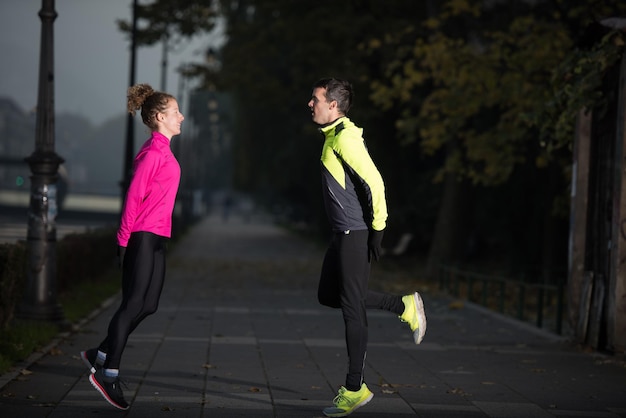 pareja de jogging calentándose y estirándose antes de correr por la mañana en la ciudad