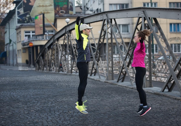 pareja de jogging calentándose y estirándose antes de correr por la mañana en la ciudad