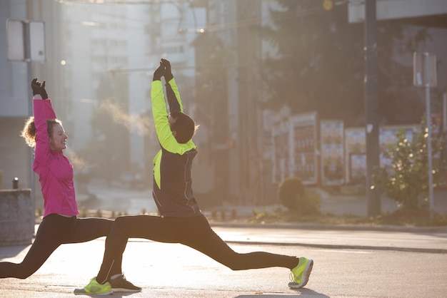 pareja de jogging calentándose y estirándose antes de correr por la mañana en la ciudad