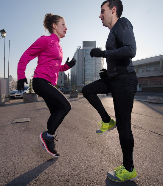 pareja de jogging calentándose y estirándose antes de correr por la mañana en la ciudad