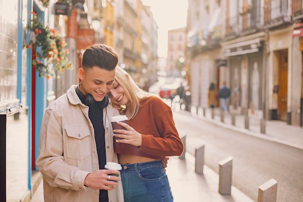 Foto una pareja joven se abraza en la calle con café para llevar