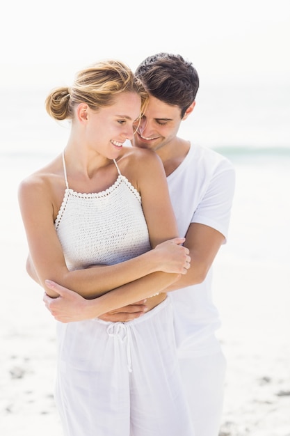 Pareja joven abrazando en la playa