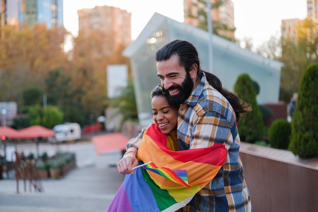 Pareja joven abrazando s con una bandera del arco iris lgtbi Concepto orgullo de estilo de vida al aire libre