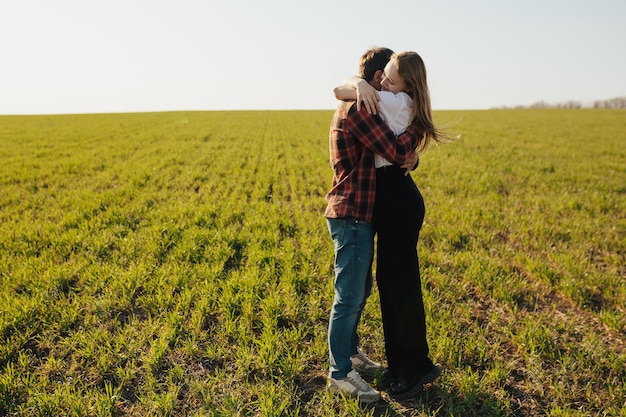 Pareja joven abrazándose en un campo de trigo en primavera.