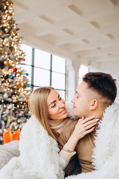 Pareja joven abrazar junto al árbol de Navidad en casa