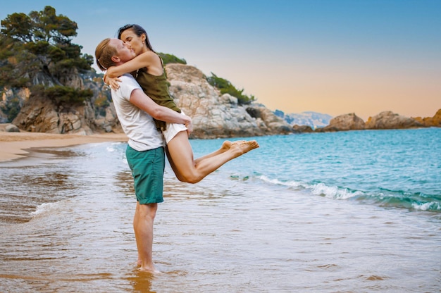 Pareja joven abrazos en la playa del mar