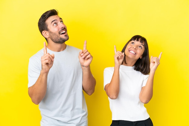 Pareja joven aislado sobre fondo amarillo apuntando con el dedo índice una gran idea