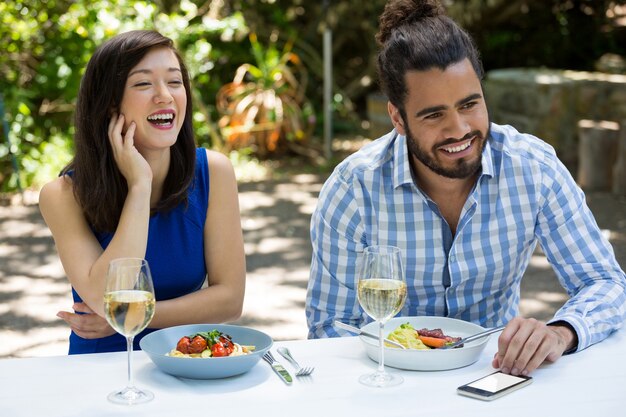 Pareja joven alegre almorzando en el restaurante al aire libre