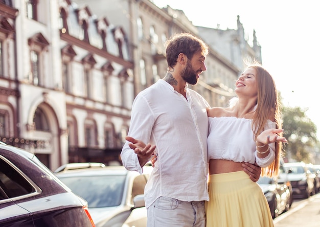 Foto una pareja joven y alegre caminando por la ciudad.