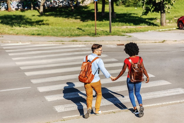 Foto pareja joven alegre corriendo por la calle y sonriendo.