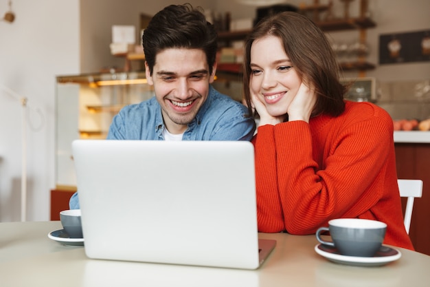 Pareja joven alegre sentado en una mesa de café