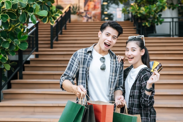 Pareja joven alegre sosteniendo múltiples bolsas de papel