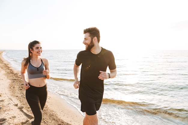 Foto pareja joven alegre trotar juntos en una playa