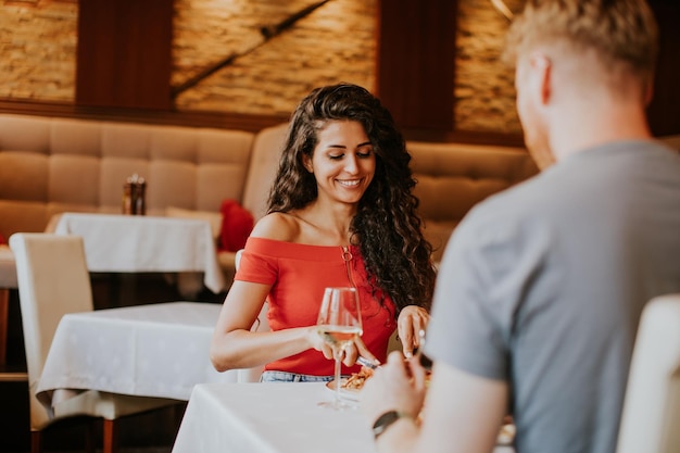 Pareja joven almorzando con vino blanco en el restaurante