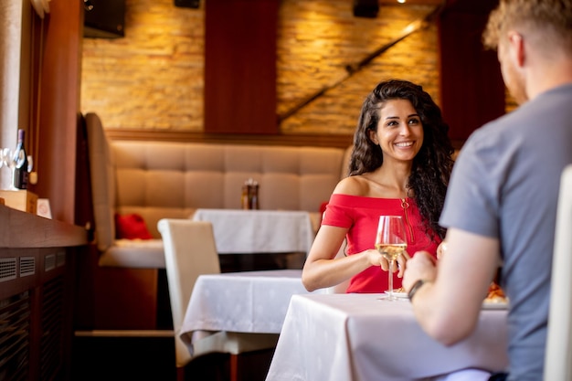 Pareja joven almorzando con vino blanco en el restaurante