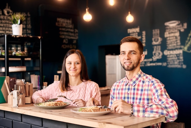 Pareja joven amigos compañeros de trabajo almorzando en un café atmosférico Pared decorada azul sobre fondo Disparos de retrato