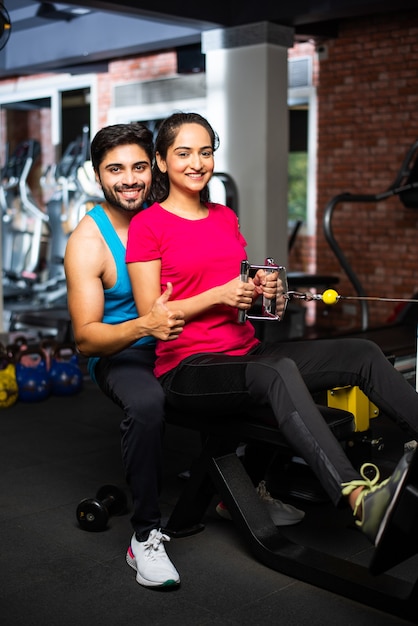 Pareja joven asiática india está trabajando en el gimnasio. Mujer atractiva y hombre guapo en forma están entrenando en el gimnasio moderno - concepto de salud y fitness