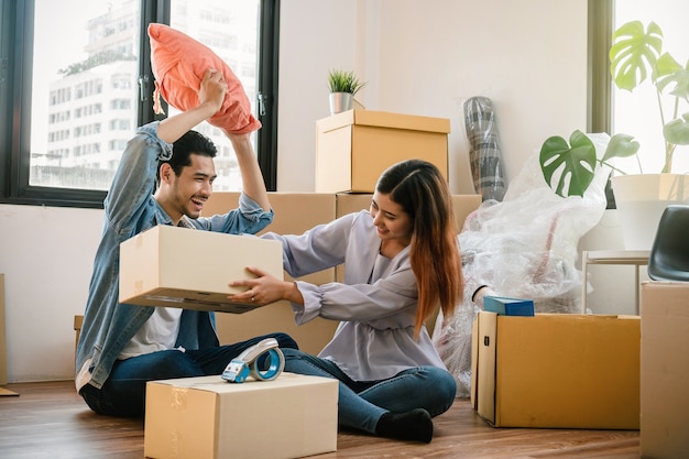 Pareja joven asiático con caja de cartón grande para mudarse en casa nueva