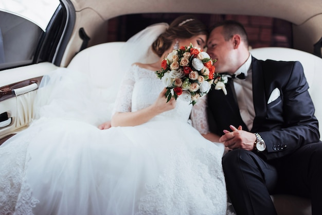 Pareja joven en un auto en el día de la boda