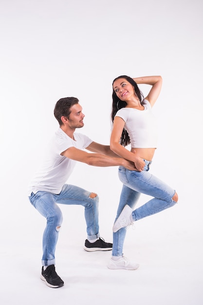 Pareja joven bailando bachata social latina, merengue, salsa. Pose de dos elegancia en la pared blanca.