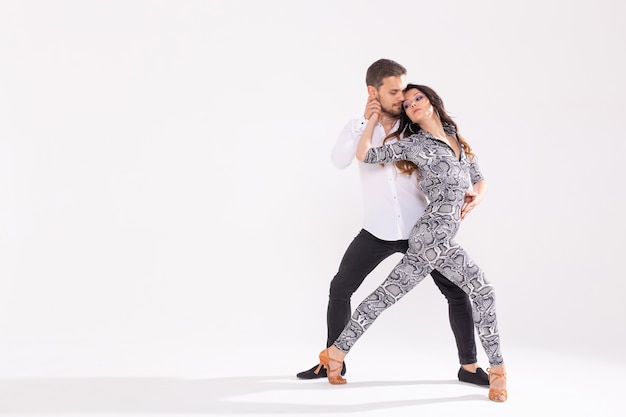 Pareja joven bailando bachata social latina, merengue, salsa. Pose de dos elegancia sobre fondo blanco con espacio de copia