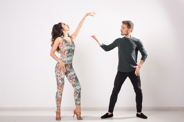 Pareja joven bailando bachata social latina, merengue, salsa. Pose de dos elegancia sobre fondo blanco.