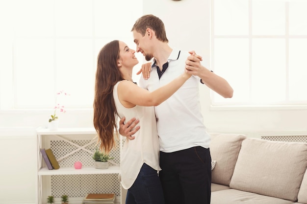 Pareja joven bailando en casa, espacio de copia. Descanso romántico, hombre y mujer divirtiéndose