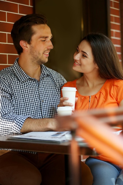 Pareja joven bebe café en la cafetería al aire libre