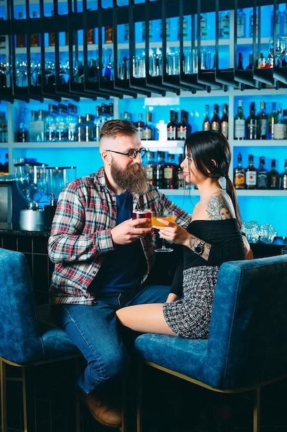 Una pareja joven bebe cócteles en el bar de un restaurante.